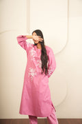 Person wearing a pink dress with white floral patterns on a white background
